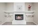 Cozy living room fireplace with decorative shelving and bright white painted brick at 6811 S Clermont Dr, Centennial, CO 80122