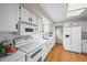 Bright kitchen featuring white appliances, white cabinets, a white countertop, and hardwood floors at 6811 S Clermont Dr, Centennial, CO 80122