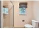 This bathroom features a functional toilet and a glass-enclosed shower, complemented by a window for natural light at 10365 E Weaver Cir, Englewood, CO 80111