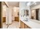 Bathroom features dual sinks, mirrors, vanities, and sliding mirrored wardrobe leading to the toilet and shower at 10365 E Weaver Cir, Englewood, CO 80111