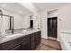 Bathroom featuring dark cabinets with granite countertops and large mirror with access to the walk-in closet at 2303 Angus St, Mead, CO 80542