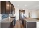 This open kitchen features dark cabinets, granite countertops, tile backsplash, and stainless steel appliances at 2303 Angus St, Mead, CO 80542