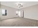 Large carpeted main bedroom with a ceiling fan, two large windows, and access to the ensuite bathroom at 2303 Angus St, Mead, CO 80542