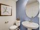 Stylish powder room with a pedestal sink, round mirror, and blue accent wall at 17145 W 91St Ln, Arvada, CO 80007