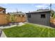 Green backyard featuring a wood fence, healthy lawn, and detached garage with two windows at 2395 N Emerson St, Denver, CO 80205
