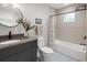 Modern bathroom features a gray vanity, round mirror, and a tub with a shower at 2395 N Emerson St, Denver, CO 80205