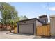 Exterior shot of the garage with grey siding, set behind a wood fence and concrete driveway at 2395 N Emerson St, Denver, CO 80205
