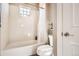 Clean bathroom featuring a white bathtub with shower and toilet with tiled walls and flooring at 11602 Pine Canyon Dr, Parker, CO 80138