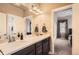 Bright bathroom featuring double sinks, spacious counter, and stylish lighting fixtures, with view to bedroom at 11602 Pine Canyon Dr, Parker, CO 80138
