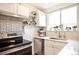 Bright kitchen features white cabinetry, stainless steel appliances, and modern tile backsplash at 1232 Wabash St, Denver, CO 80220