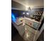 Modern basement bar area boasts sleek white cabinets, a mini-fridge, and open shelving displaying an assortment of liquors at 300 S Lincoln St, Denver, CO 80209