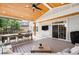 Open, airy back deck with vaulted wood ceiling, outdoor dining table, seating area and outdoor television at 16658 Black Oak Ct, Parker, CO 80134