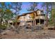 Multi-level deck on a beautiful home with a rocky backyard landscape, surrounded by mature trees at 30082 Troutdale Ridge Rd, Evergreen, CO 80439