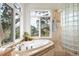 Bright bathroom features a soaking tub with a scenic outdoor view and a glass block shower at 30082 Troutdale Ridge Rd, Evergreen, CO 80439