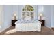 Serene bedroom featuring a large arched window with shutters and two bedside lamps at 30082 Troutdale Ridge Rd, Evergreen, CO 80439