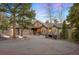 Charming home with a large circular driveway surrounded by mature pine trees and a well-maintained front yard at 30082 Troutdale Ridge Rd, Evergreen, CO 80439