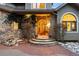 Stone archway entry with a beautifully crafted wooden door and well-manicured landscape at 30082 Troutdale Ridge Rd, Evergreen, CO 80439