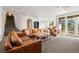 Spacious living room with carpet flooring and a large leather sofa set; sliding glass doors to the outside at 30082 Troutdale Ridge Rd, Evergreen, CO 80439