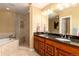 Luxurious bathroom with double sinks, a large mirror, a soaking tub, and tiled shower at 5549 Lake Gulch Rd, Castle Rock, CO 80104