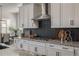 Modern kitchen with white cabinetry, dark backsplash, stainless steel appliances, and gas stove at 3256 Offbeaten Pl, Castle Rock, CO 80108