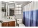 A well-lit bathroom with a modern vanity, toilet, and shower with a blue and white curtain at 5570 Nepal St, Denver, CO 80249