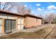 Exterior view of a brick home showing a sliding door, window wells and concrete patio at 2695 S Josephine St, Denver, CO 80210
