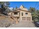 Inviting exterior features a two-car garage and a staircase leading to an elevated entrance, blending with nature at 268 Cedar Rd, Golden, CO 80401