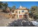 View of house featuring a two-car garage and elevated entrance, nestled in a serene, wooded landscape at 268 Cedar Rd, Golden, CO 80401