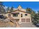 Inviting multi-level exterior with wood staircase, two car garage, and neutral stucco under a bright blue sky at 268 Cedar Rd, Golden, CO 80401