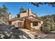 Exterior side view of multi-level stucco home with wood deck, staircase, mature trees and mountain views at 268 Cedar Rd, Golden, CO 80401