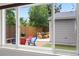 Backyard view from inside through sliding glass doors highlighting colorful chairs and outdoor dining at 3241 Sheridan Blvd, Wheat Ridge, CO 80212