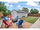 Cozy backyard with firepit, chairs, a synthetic grass area, and an outdoor dining set next to a garage at 3241 Sheridan Blvd, Wheat Ridge, CO 80212