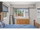 Bright bedroom featuring a wooden dresser, large window overlooking backyard, and blue bedding at 3241 Sheridan Blvd, Wheat Ridge, CO 80212