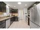 Modern kitchen featuring stainless steel appliances, dark cabinets, and tile floors at 3241 Sheridan Blvd, Wheat Ridge, CO 80212