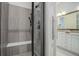 Modern bathroom featuring tiled walk-in shower with bench, glass door, and a vanity with white cabinets at 24963 E Phillips Pl, Aurora, CO 80016