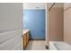 Bathroom with blue painted wall and tan tiled shower and flooring, next to white door at 2080 S Danube Ct, Aurora, CO 80013