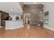 Bright living room featuring wood floors, a wood accent wall, and an open floor plan to the kitchen at 2080 S Danube Ct, Aurora, CO 80013
