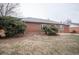 Quaint backyard with mature trees surrounding a cozy brick home at 840 Tucson St, Aurora, CO 80011