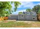 Back of house and yard with new gray siding, white trim, and new wooden fence on a sunny day at 1705 Cathay Ct, Aurora, CO 80011