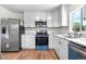 Bright kitchen featuring modern stainless steel appliances, white cabinets, and hardwood floors at 1705 Cathay Ct, Aurora, CO 80011