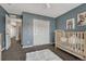 Bedroom with blue accent wall, plush white rug, wood-look crib, and closet space at 22965 Allendale Ave, Parker, CO 80138