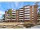 Apartment building featuring multiple balconies and mature trees against a bright blue sky at 2880 S Locust St # 704N, Denver, CO 80222