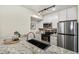 Modern kitchen with granite countertops, a black sink, stainless steel appliances, and sleek white cabinets at 2880 S Locust St # 704N, Denver, CO 80222