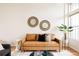 Cozy living room with tan leather sofa, round mirrors, and a vibrant green plant next to a large window at 2680 Blake St # 12, Denver, CO 80205