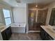 Elegant bathroom featuring a soaking tub, glass-enclosed shower, and double vanities with dark wood cabinets at 16654 W 93Rd Way, Arvada, CO 80007