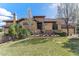 Beautiful two-story home with a tile roof, chimney, manicured lawn, and mature landscaping at 7850 Vallagio Ln, Englewood, CO 80112