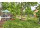 Spacious backyard with a wood deck, lush lawn, mature trees, and garden beds at 912 S Galena St, Aurora, CO 80247