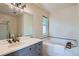 Bathroom featuring tile floors, vanity with sink, large tub, and small window for natural light at 912 S Galena St, Aurora, CO 80247