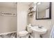 Stylish half bath with pedestal sink, geometric shelving, and modern laundry signage at 8432 S Upham Way, Littleton, CO 80128