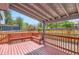 Covered wooden deck featuring built-in bench seating and a view of the landscaped backyard at 8432 S Upham Way, Littleton, CO 80128